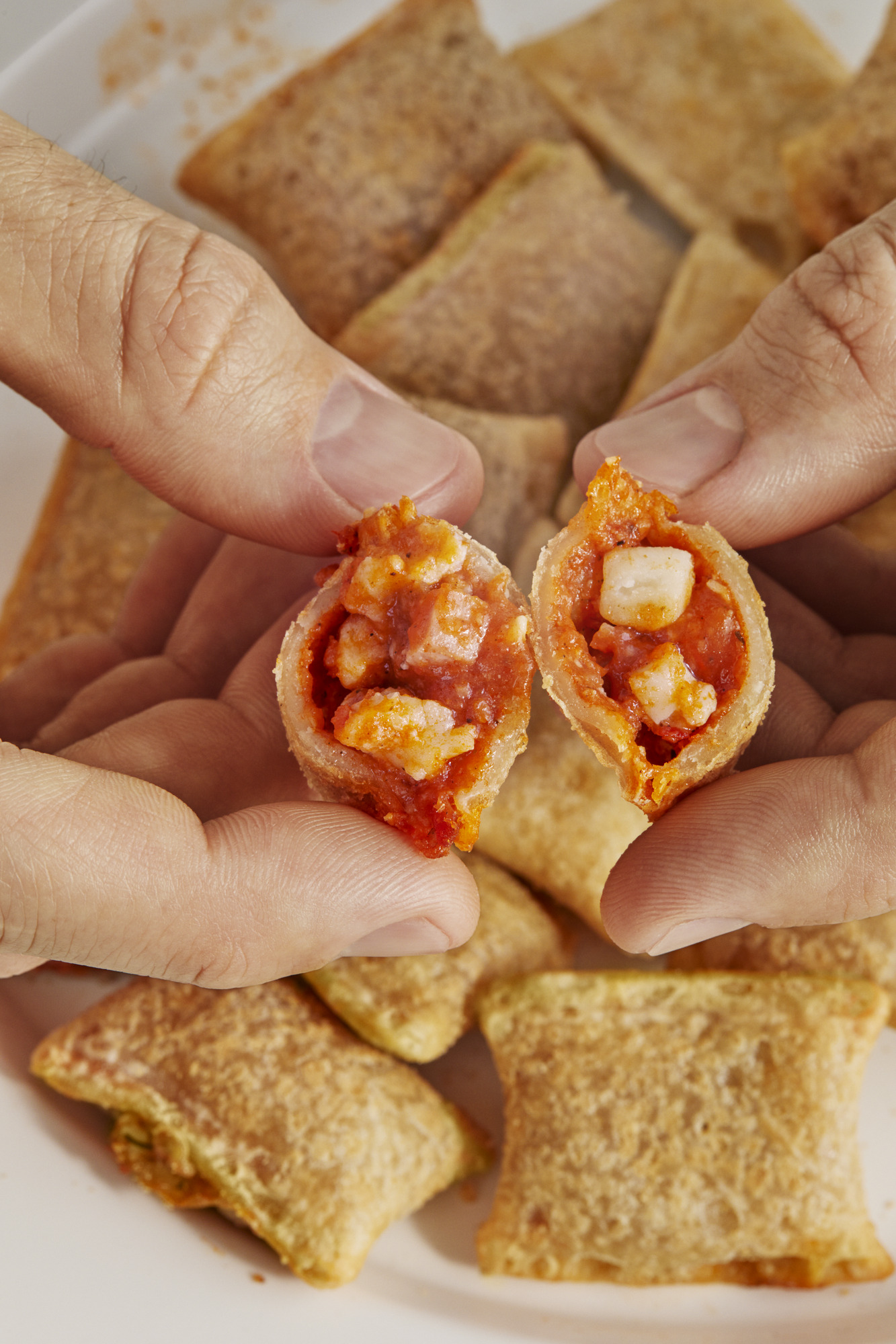 Pair of hands opening a Totino's pizza roll