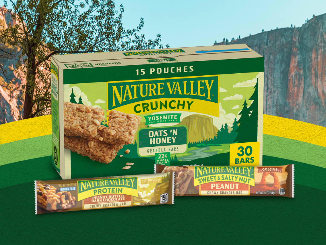 ​​Nature Valley Oats 'n Honey Crunchy Granola Bars box and individually wrapped Protein Peanut Butter Dark Chocolate and Sweet & Salty Nut Peanut bars in limited-edition National Parks-inspired packaging, displayed against a scenic national park backdrop.